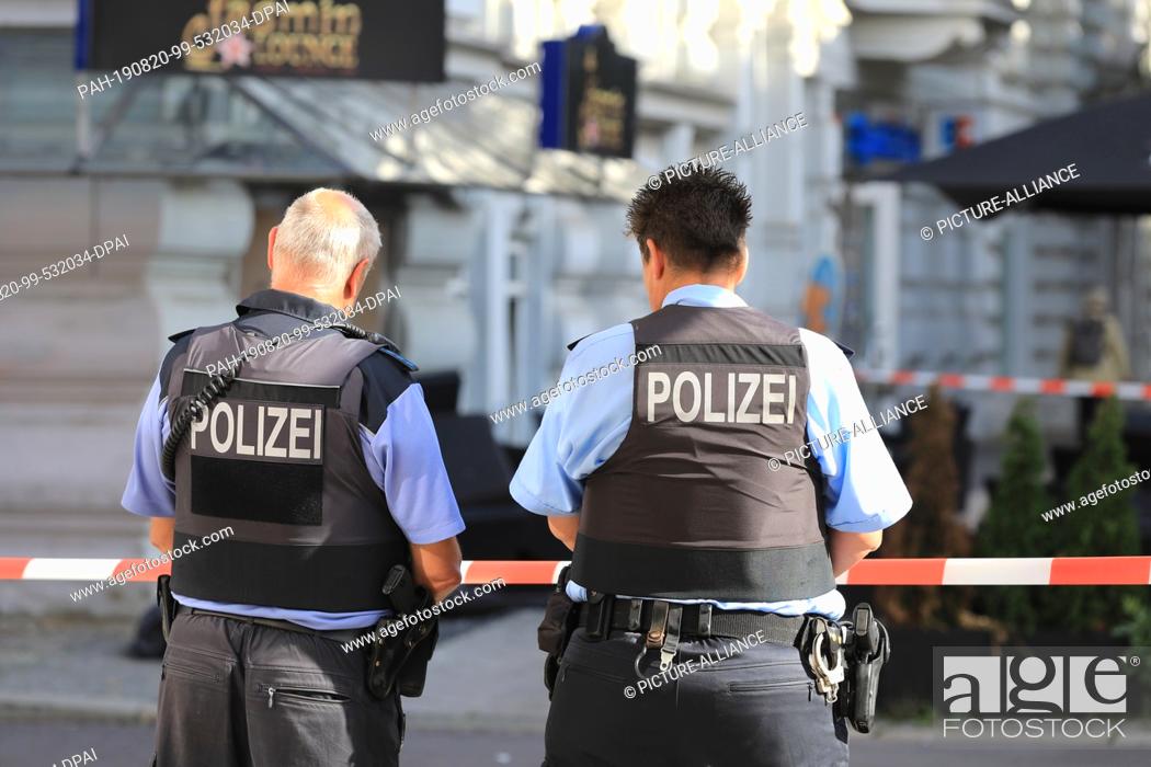 Stock Photo: 20 August 2019, Saxony-Anhalt, Magdeburg: Policemen are standing in front of a restaurant in the state capital. At least two people were injured during the.