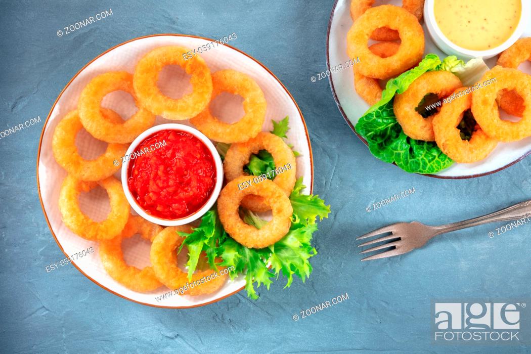Stock Photo: Calamari rings. Deep fried squid rings with lettuce and various sauces, overhead flat lay shot on a blue background.