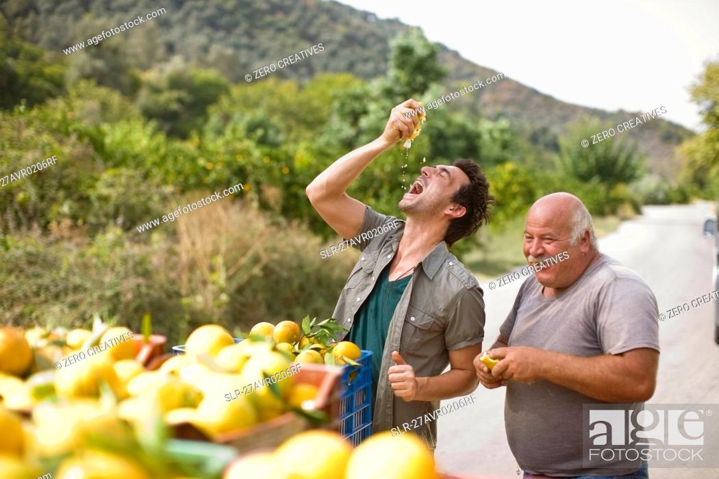 Stock Photo: Men squashing oranges.