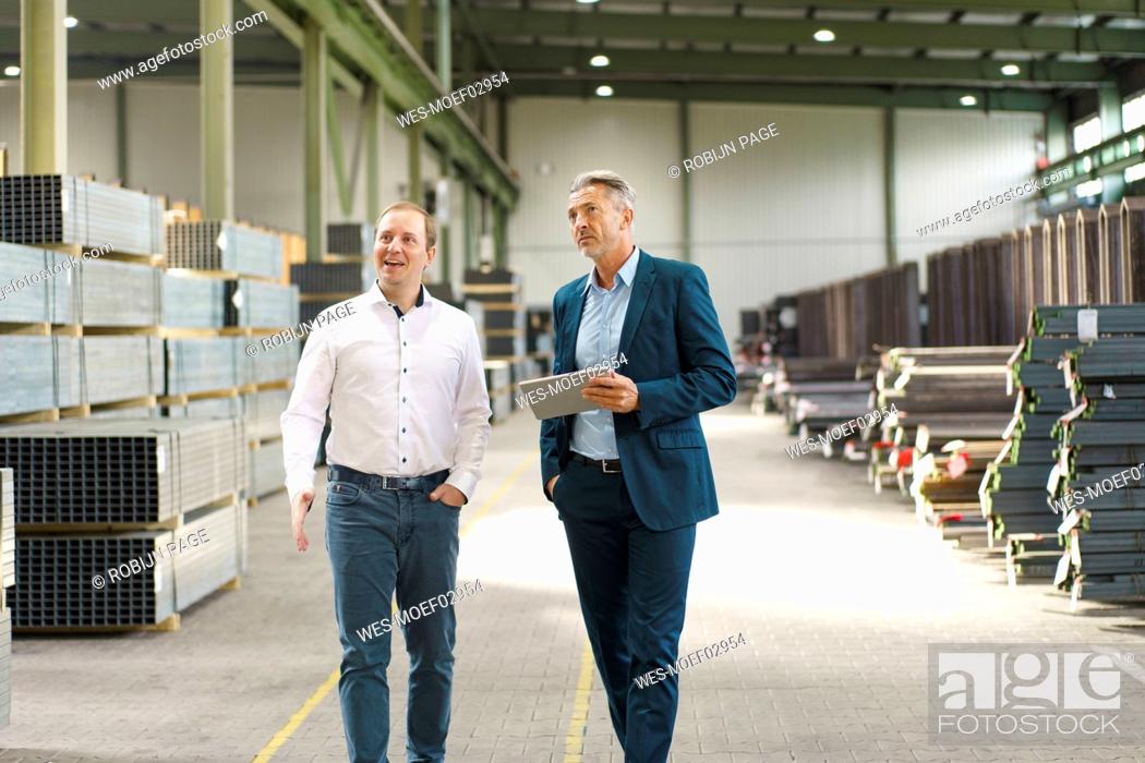 Stock Photo: Two businessmen having a meeting and walking in a factory.