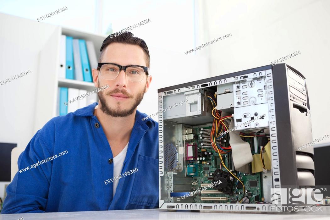 Stock Photo: Computer engineer smiling at camera beside open console.