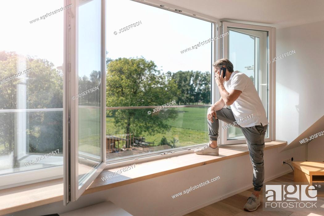 Stock Photo: Mature man on the phone at the window in empty room.