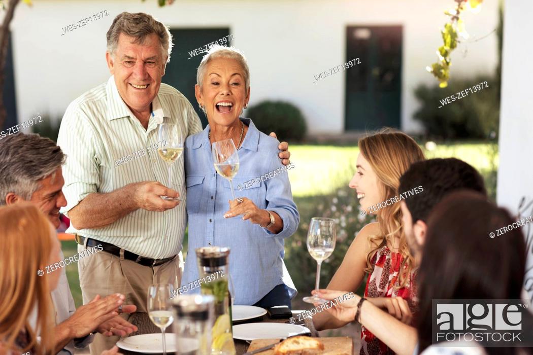 Stock Photo: Happy senior couple with family having lunch together outside.