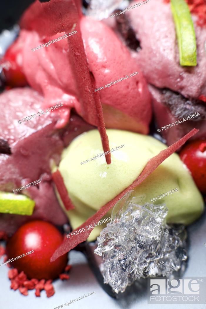 Stock Photo: Strawberry and pistachio ice cream with cherries in a black bowl.