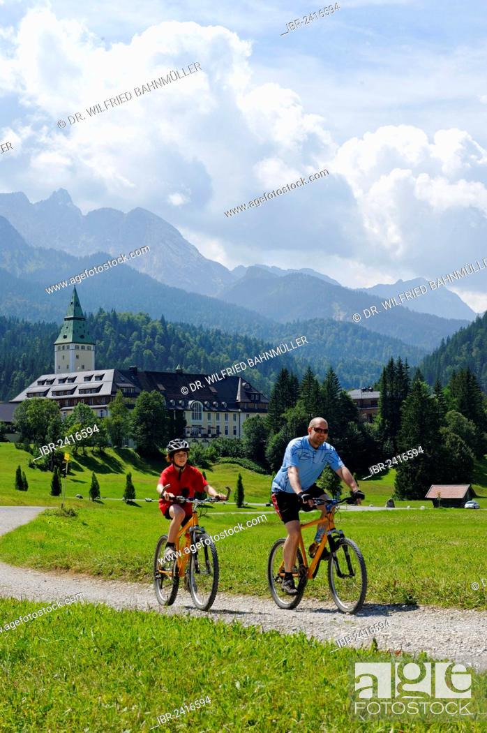 Stock Photo: Cycling tour with mountain bikes, father and son in front of Schloss Elmau Castle, Mittenwald, Wetterstein Range, Werdenfelser Land, Upper Bavaria, Bavaria.