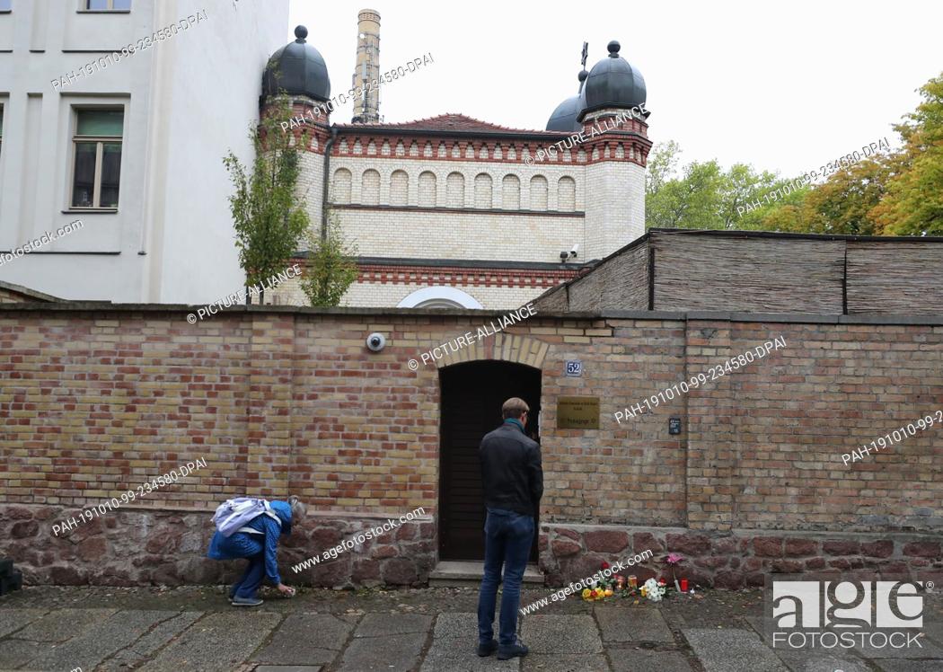 Stock Photo: 10 October 2019, Saxony-Anhalt, Halle: People lay flowers and candles in front of the synagogue. During attacks in the middle of Halle an der Saale in.