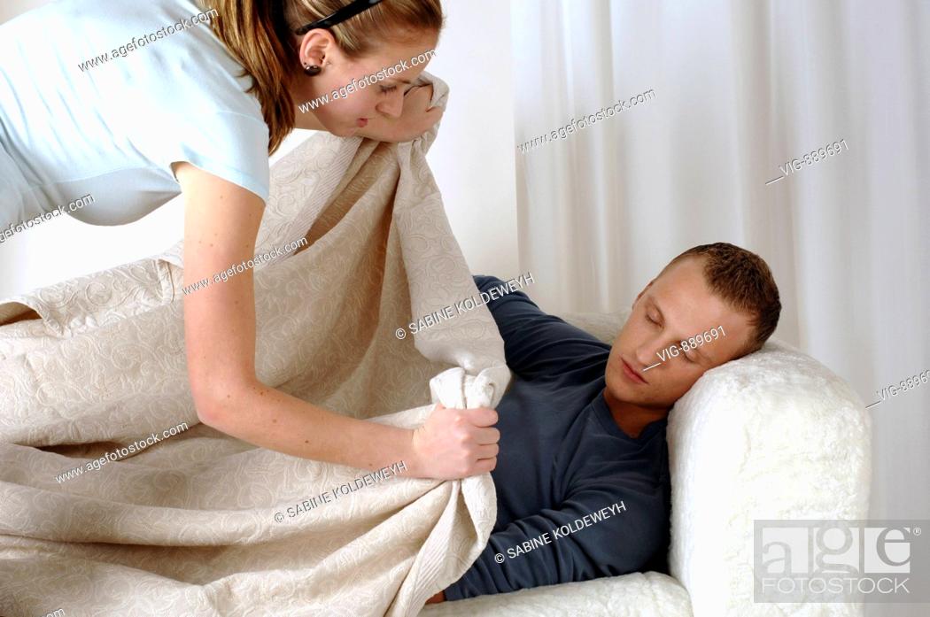 Stock Photo: Young woman carpets her sleeping boyfriend on a sofa. - 30/06/2008.