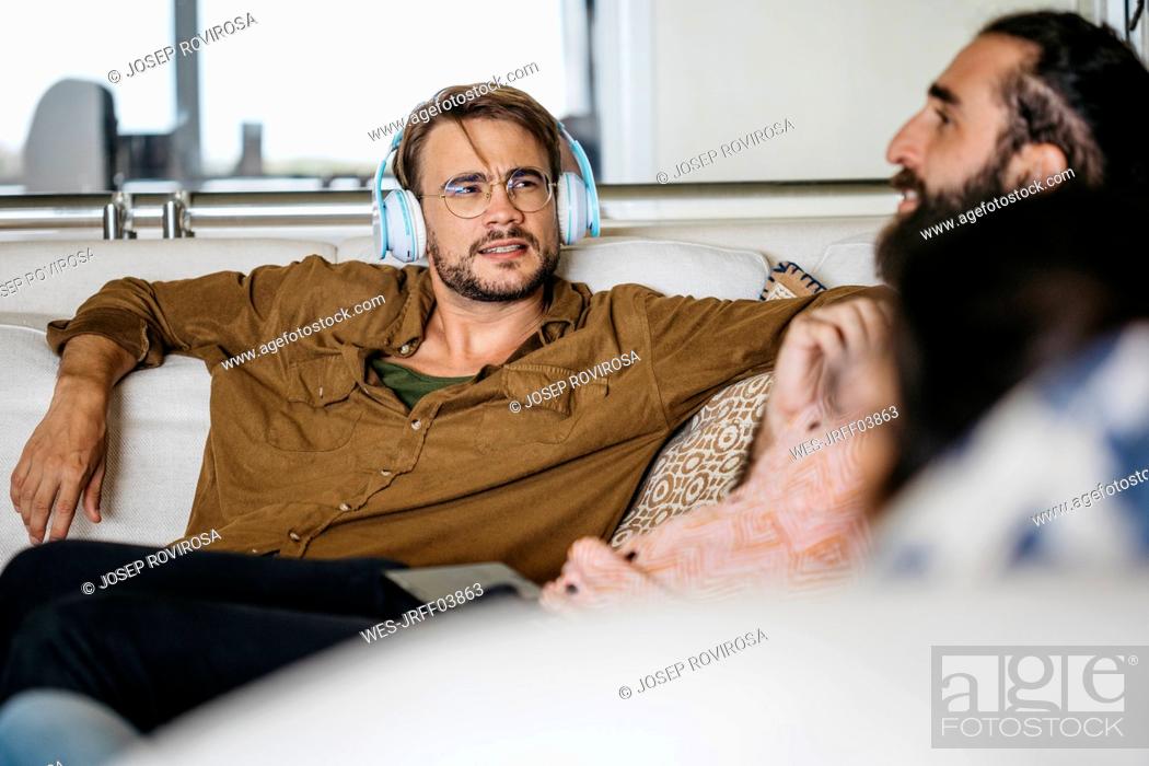 Stock Photo: Friends sitting on couch together, talking and listening music.