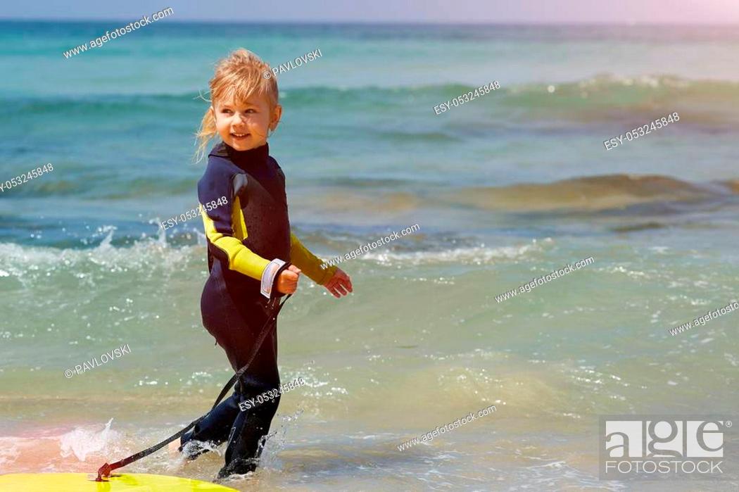 Photo de stock: Little baby girl - young surfer with bodyboard has fun on sea beach. Family lifestyle, people outdoor water sport lessons and swimming activity on summer.