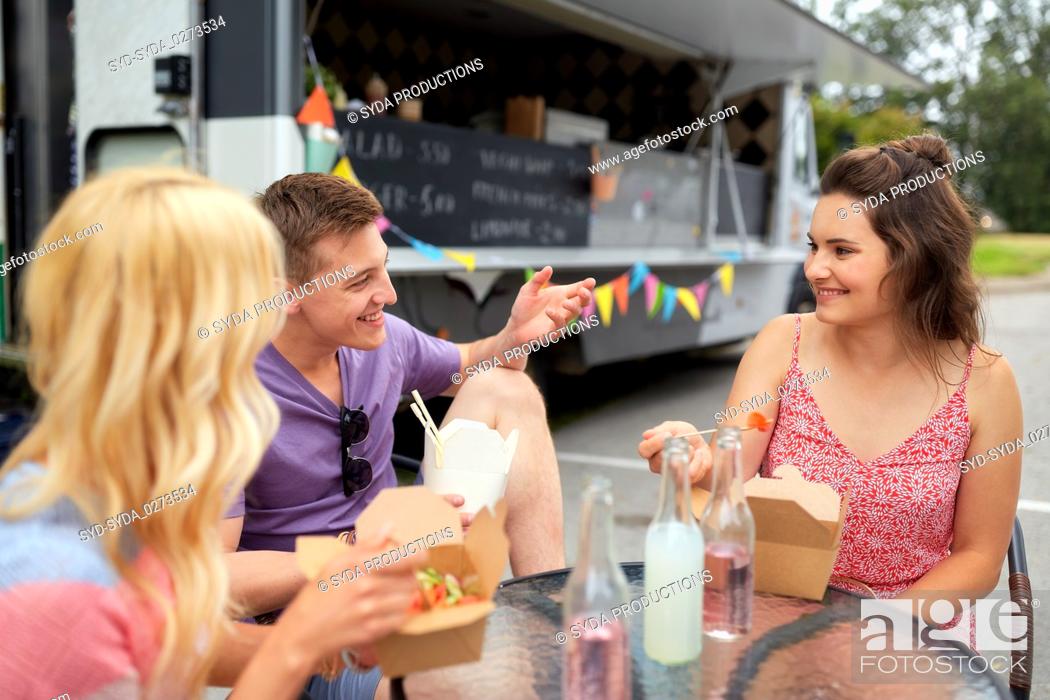 Stock Photo: happy friends with drinks eating at food truck.