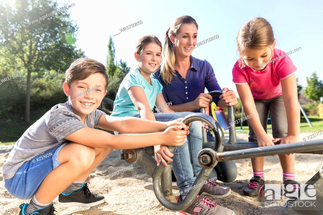 Stock Photo: Mother and kids in sandbox playing with digger.