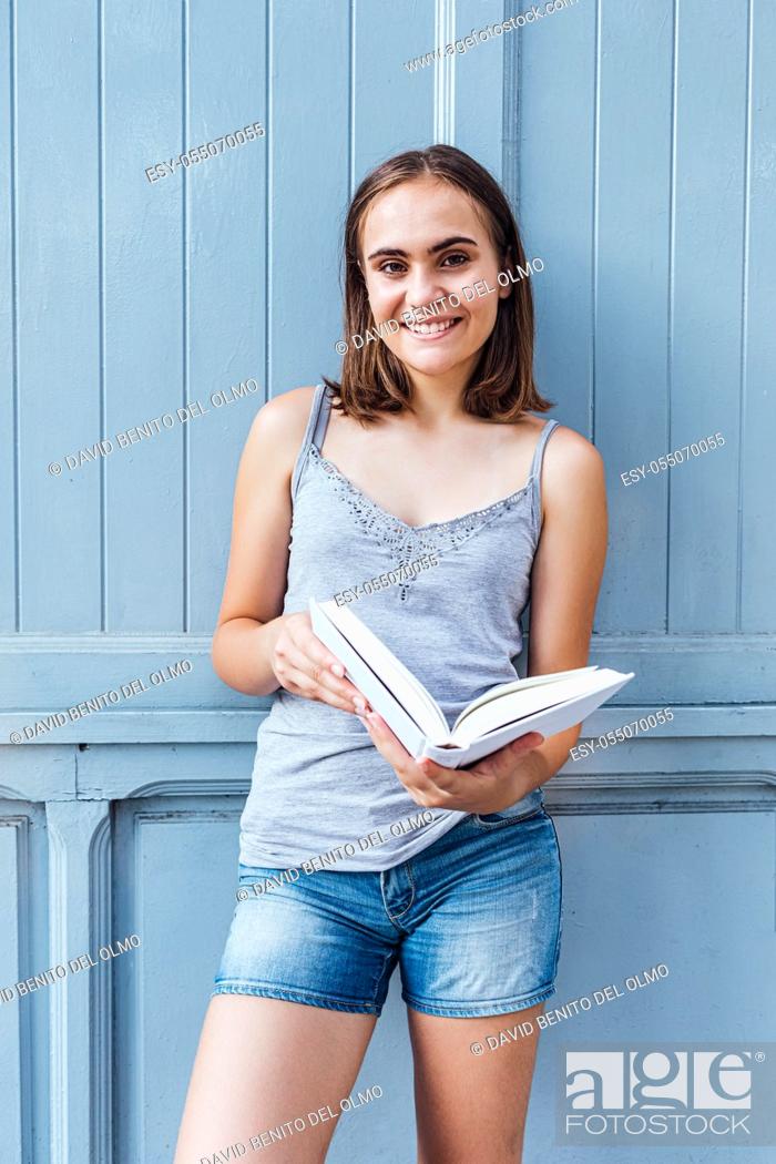 Stock Photo: Young girl smiles and holds a bluish gray open white paper.