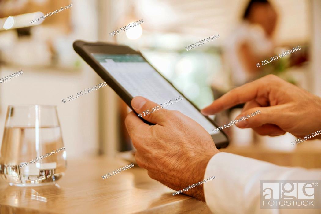 Stock Photo: Close-up of man using tablet in a cafe.