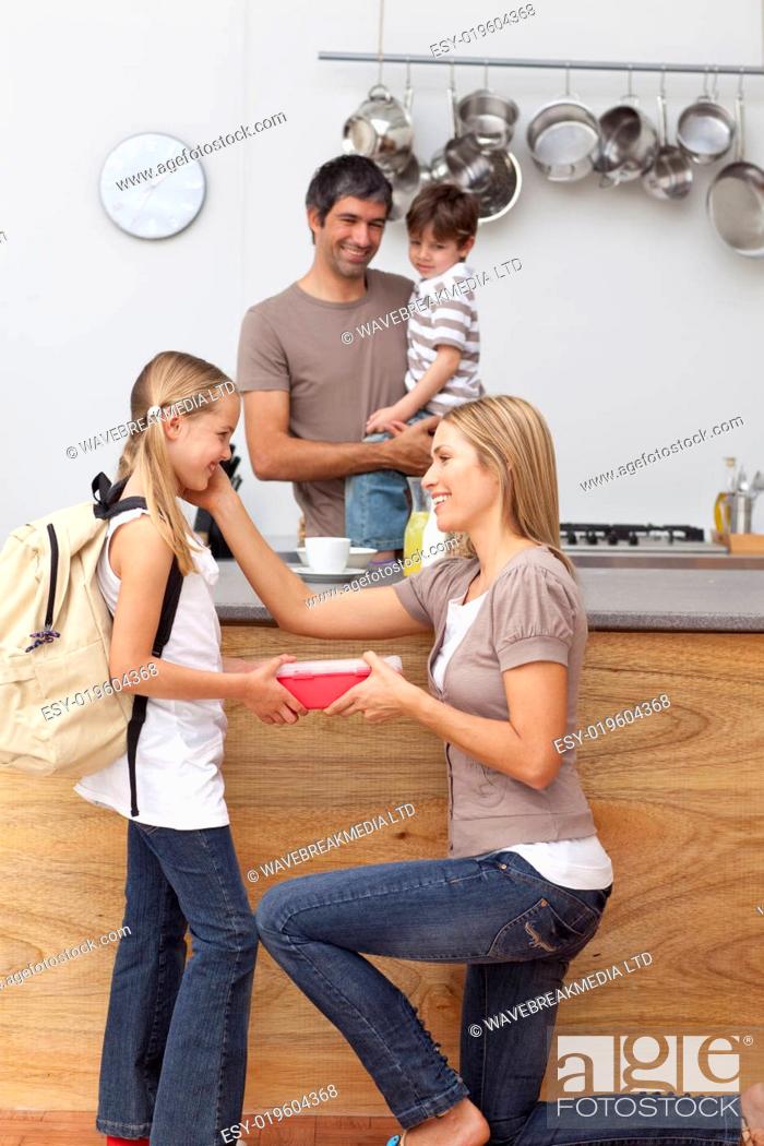 Stock Photo: Mother giving girl the school lunch in the kitchen.