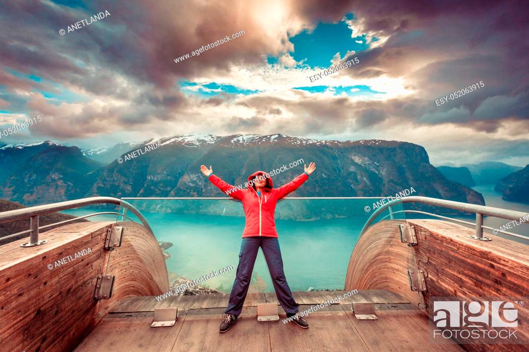 Stock Photo: Tourist woman on Stegastein viewpoint enjoying Aurland fjord view with arms raised outstretched up, Sogn Og Fjordane, Norway.