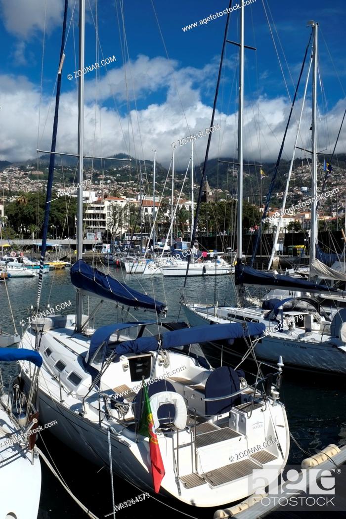 Stock Photo: Segelyachten im Sporthafen von Funchal, dahinter die Stadt mit dicht 					besiedelten Haengen. Hochformat. Sailing boats in the sports harbour of Funchal.