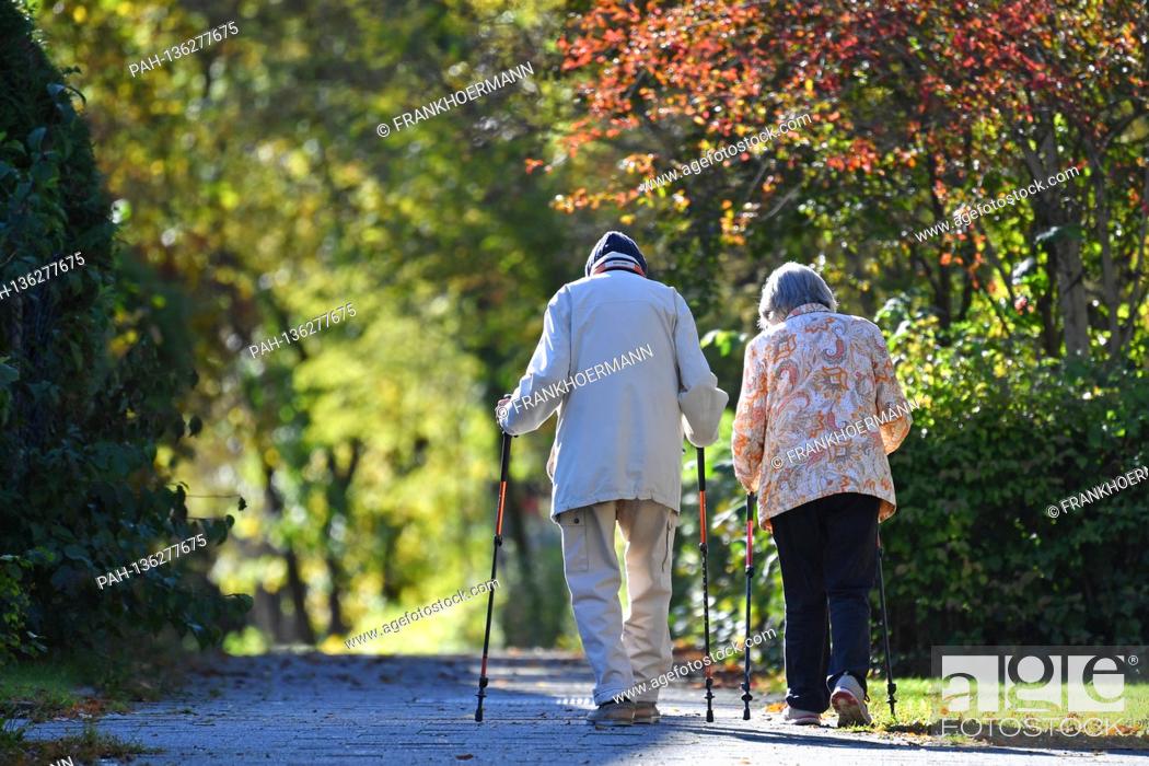Stock Photo: Old married couple pensioner man and woman go for a walk with Nordic walking sticks. | usage worldwide. - Munich/Bayern/Deutschland.