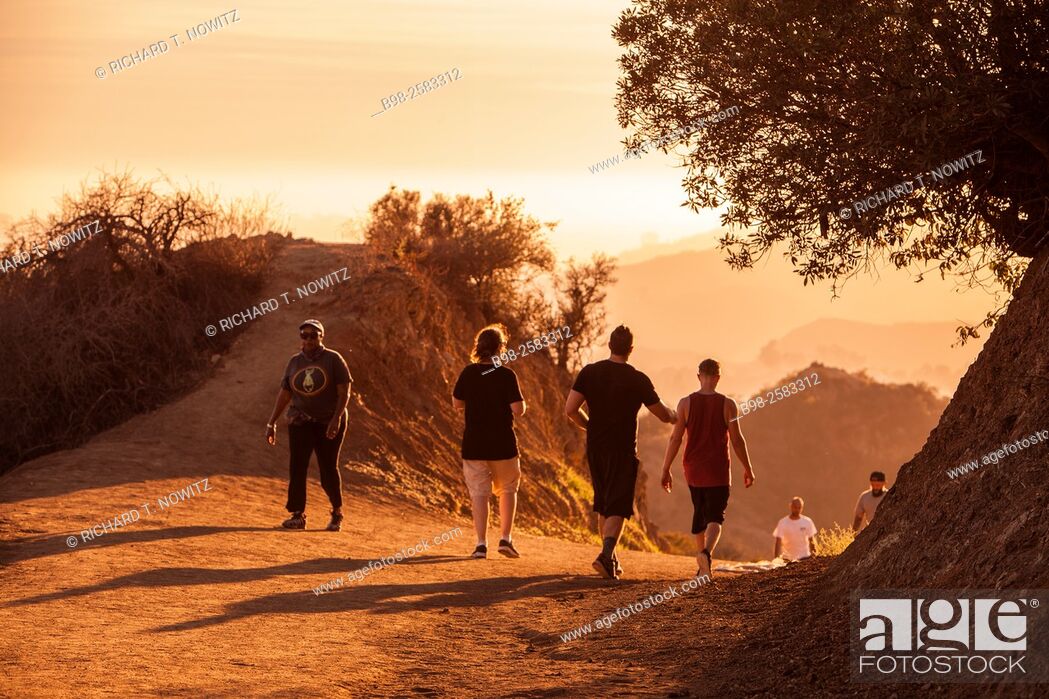 Stock Photo: A small group of people walking on a hiking trail at sunset in the Hollywood Hills of Griffith Park, Los Angeles.
