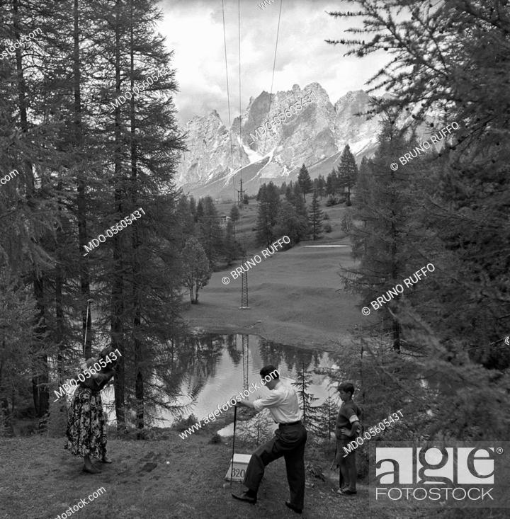 Stock Photo: Italian motorcycle racing driver Bruno Ruffo playing golf with his wife. Cortina d'Ampezzo, 1950s.