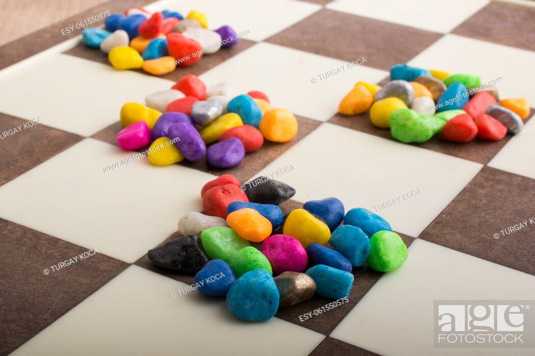 Stock Photo: Colorful pebbles spread on checked board background.