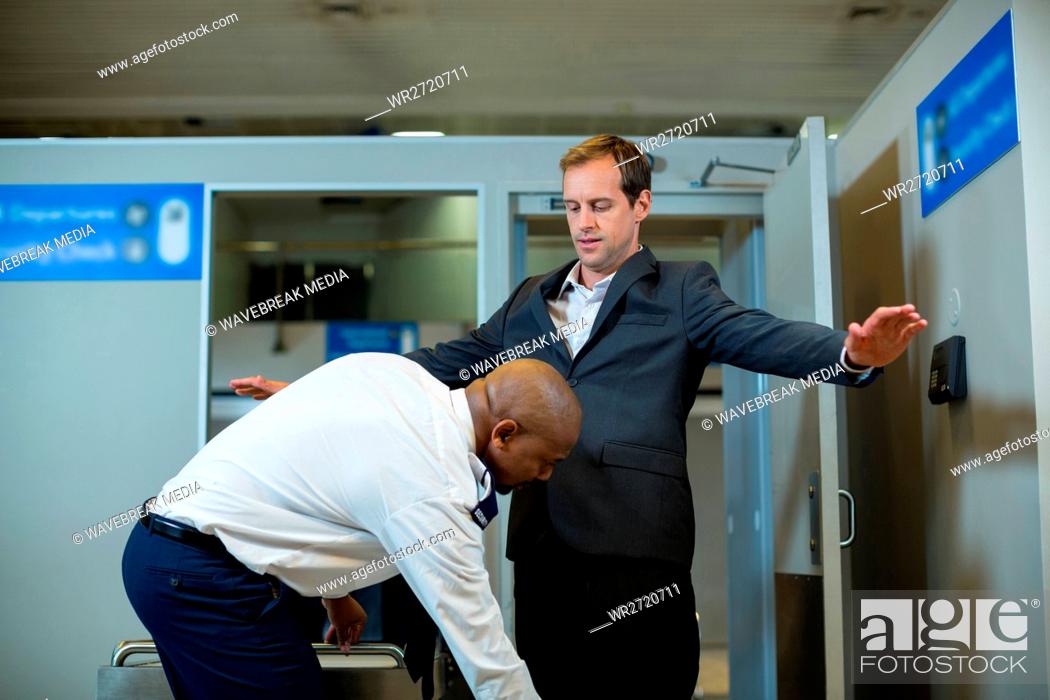Stock Photo: Airport security officer using a hand held metal detector to check a commuter.