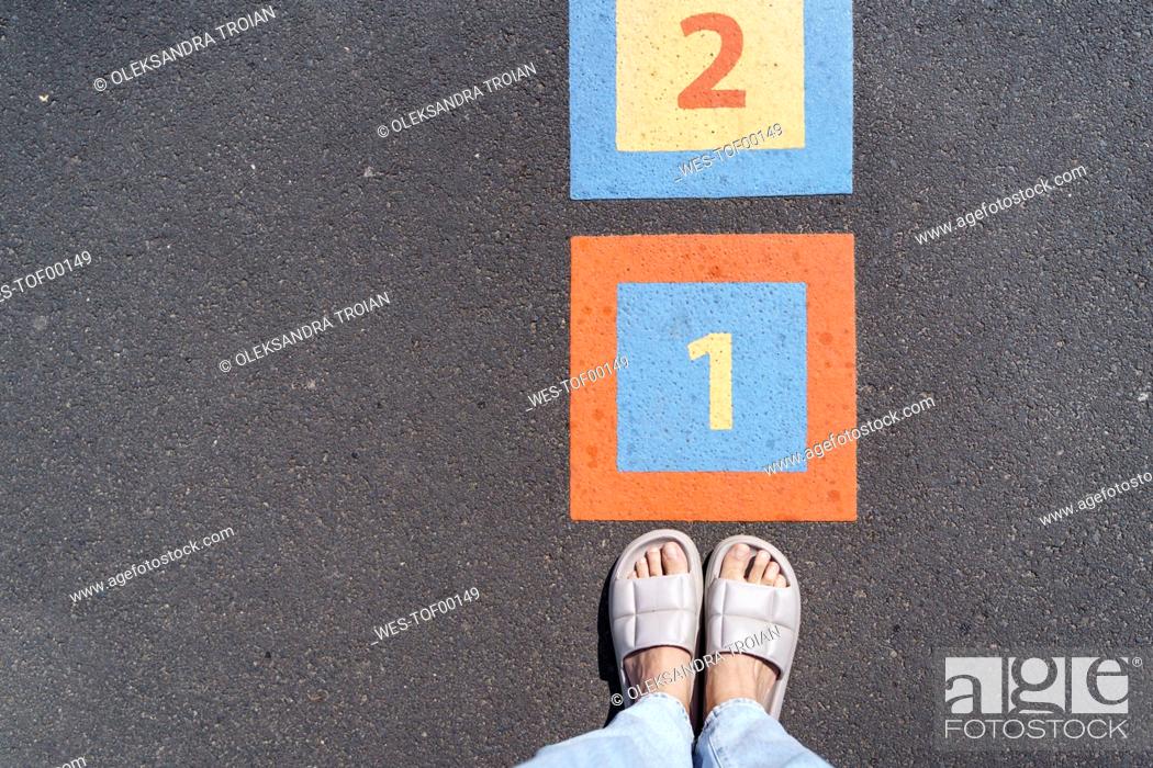 Stock Photo: Legs of woman by number on footpath.