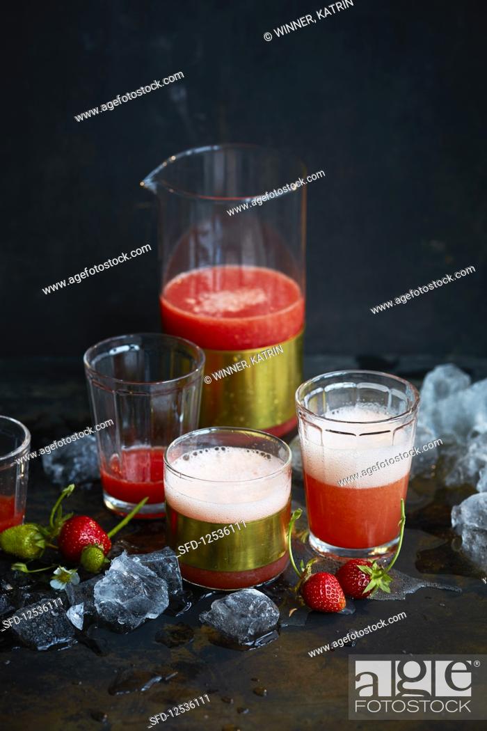 Stock Photo: Strawberry drink in a carafe and glasses against a black background.
