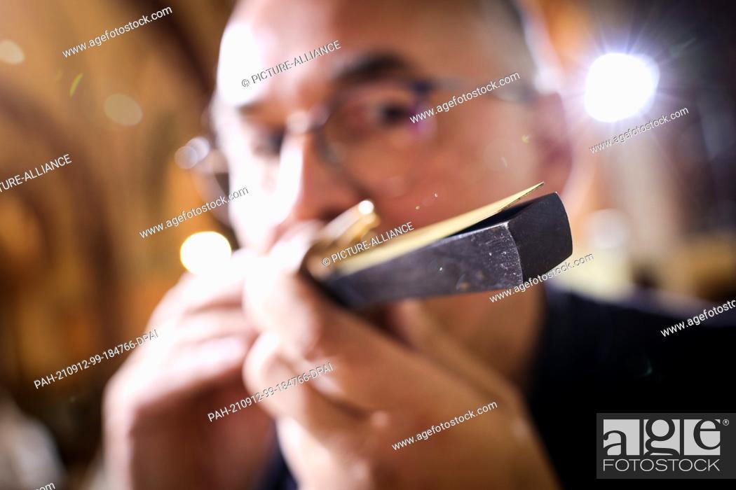 Stock Photo: PRODUCTION - 23 August 2021, Schleswig-Holstein, Schleswig: Ekkehard Fehl, organ builder, checks a reed pipe/lingual pipe of the great organ in Schleswig.