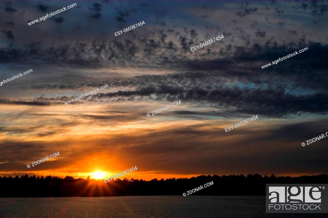 Stock Photo: Dramatic and colorful sunset over a forest lake reflected in the water. Blakheide, Beerse, Belgium. High quality photo.