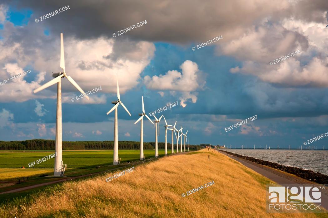 Stock Photo: Dutch Windturbines and a cloudscape in the last sunlight of a summer evening.