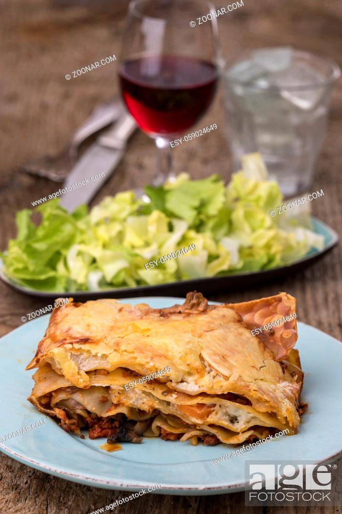 Stock Photo: lasagna with salad on dark wood.