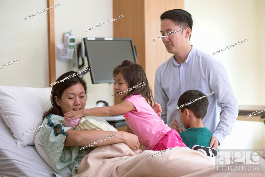 Stock Photo: Family admiring newborn baby in hospital room.