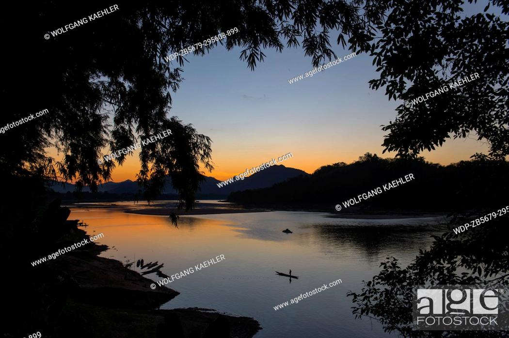 Stock Photo: View of the Mekong River with a fisherman in a boat after sunset near the UNESCO world heritage town of Luang Prabang in Central Laos.