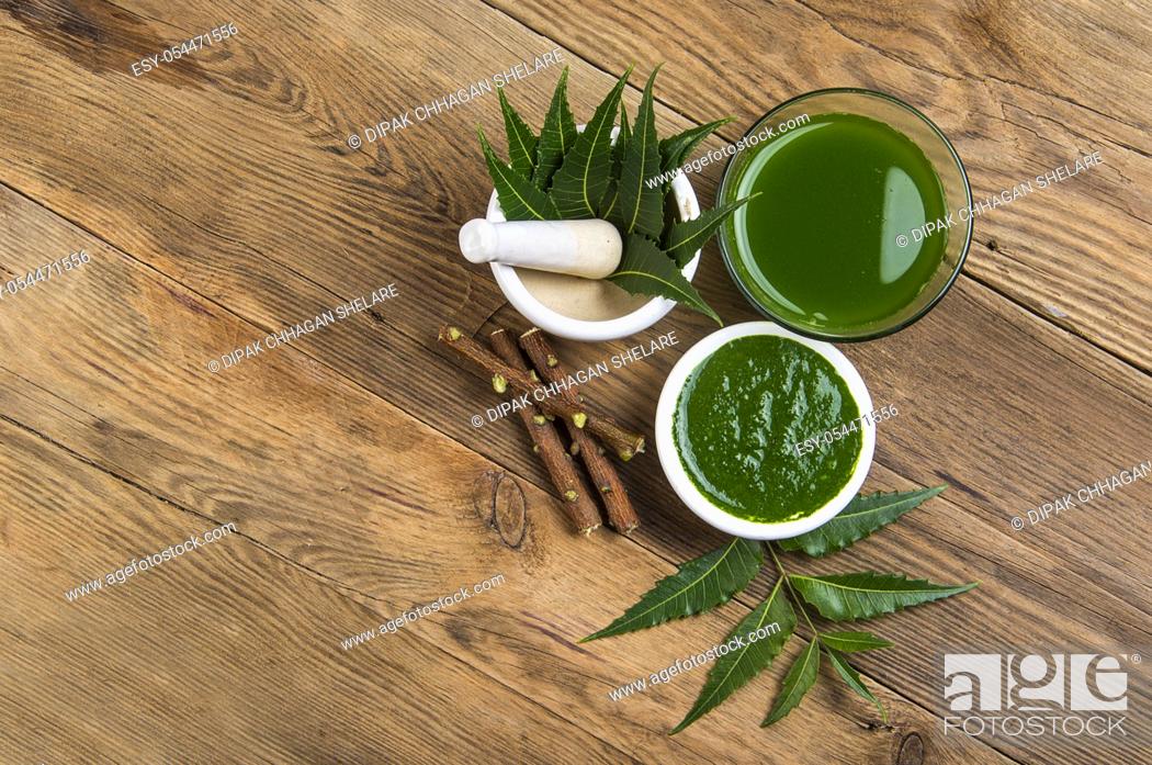Stock Photo: Medicinal Neem leaves in mortar and pestle with neem paste, juice and twigs on wooden background.