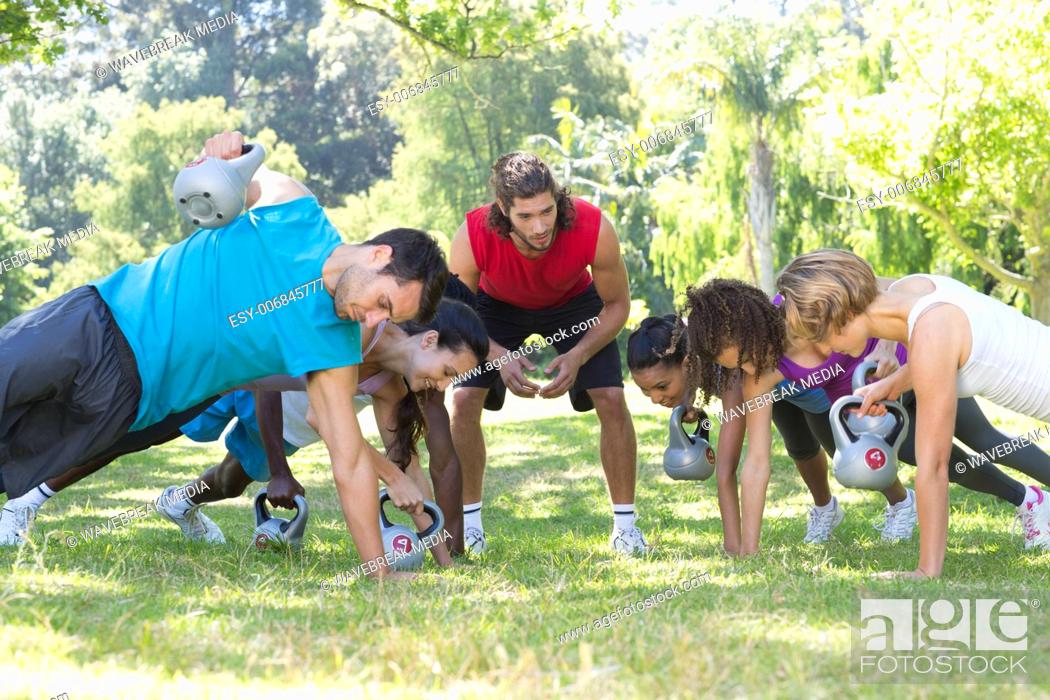 Stock Photo: Fitness group planking in park with coach.