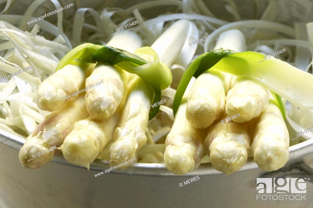 Stock Photo: Two bundles of asparagus on asparus peelings in colander.