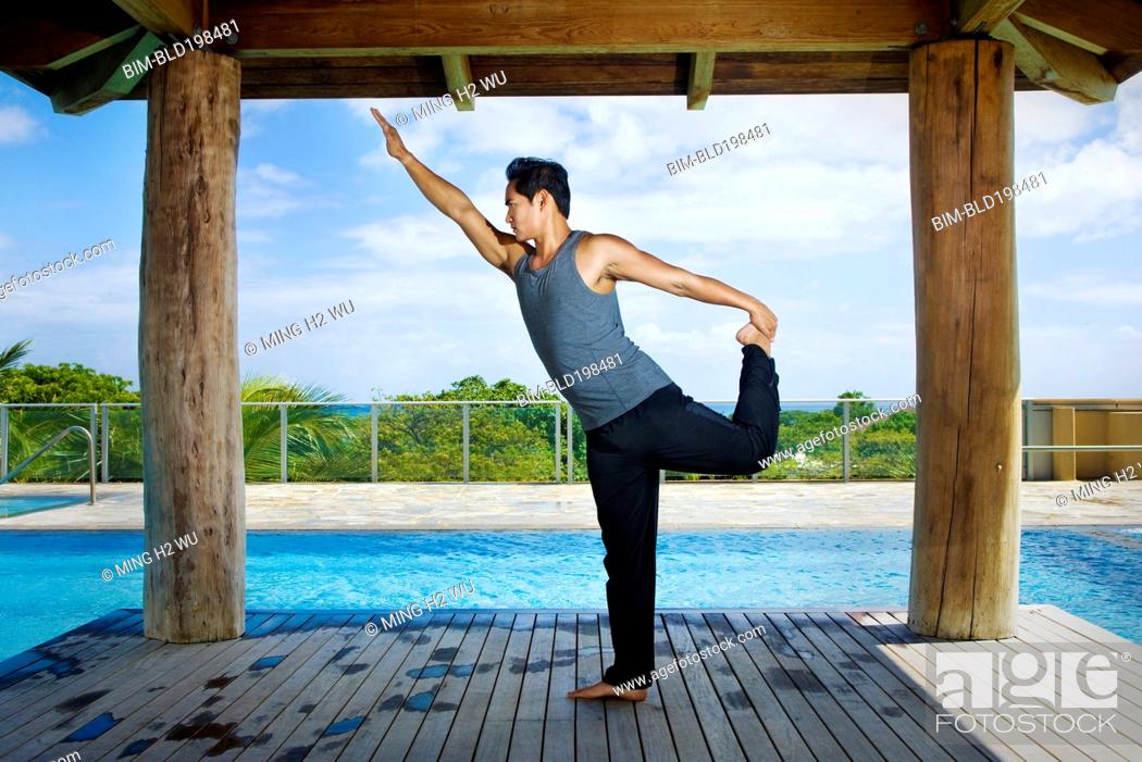 Stock Photo: Asian man practicing yoga at poolside.