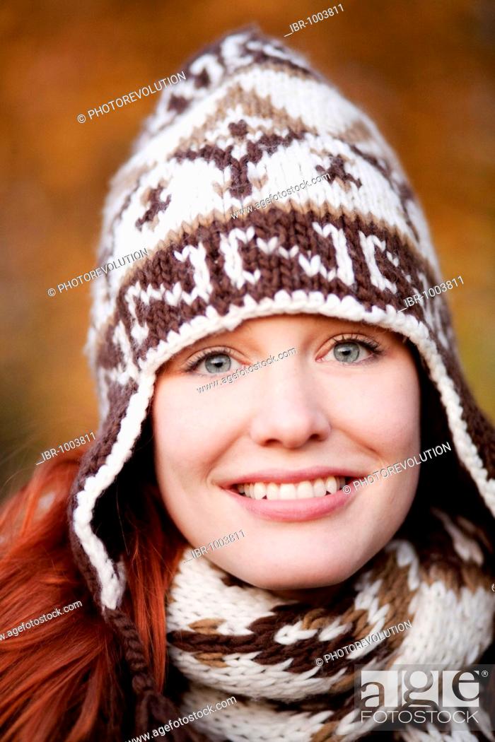 Stock Photo: Young red haired woman wearing a woolen hat and scarf, portrait.