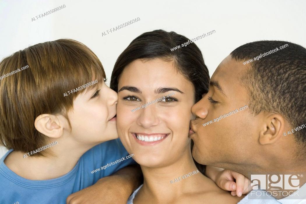 Stock Photo: Husband and son kissing woman's cheeks, woman smiling at camera.