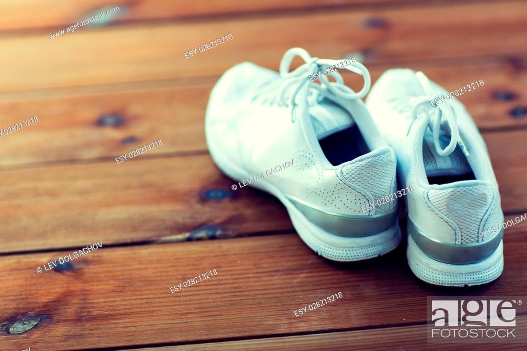 Stock Photo: sport, fitness, shoes, footwear and objects concept - close up of sneakers on wooden floor.
