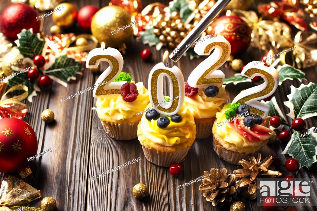 Stock Photo: New year cupcakes with number candles being lit by gas lighter.