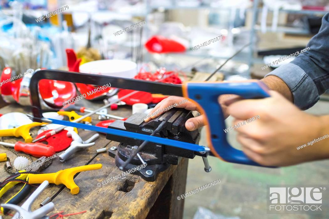 Stock Photo: Man working with saw on fencing weapon on workbench.