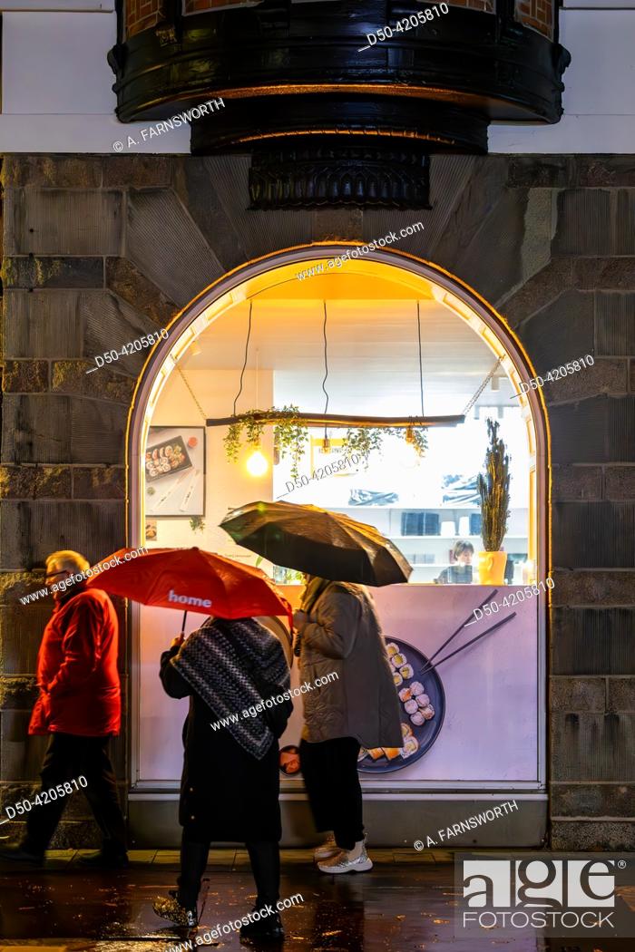 Photo de stock: Odense, Denmark People walking on the sidewalk with umbrellas in the rain.