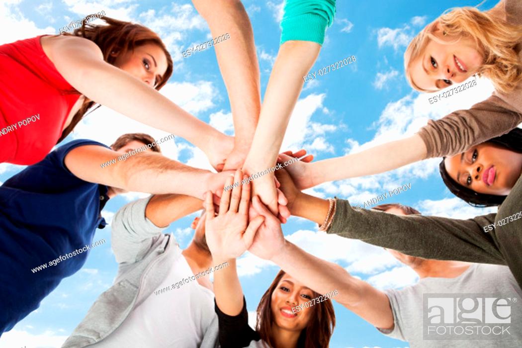 Stock Photo: Low angle view of young college students stacking hands against white background.