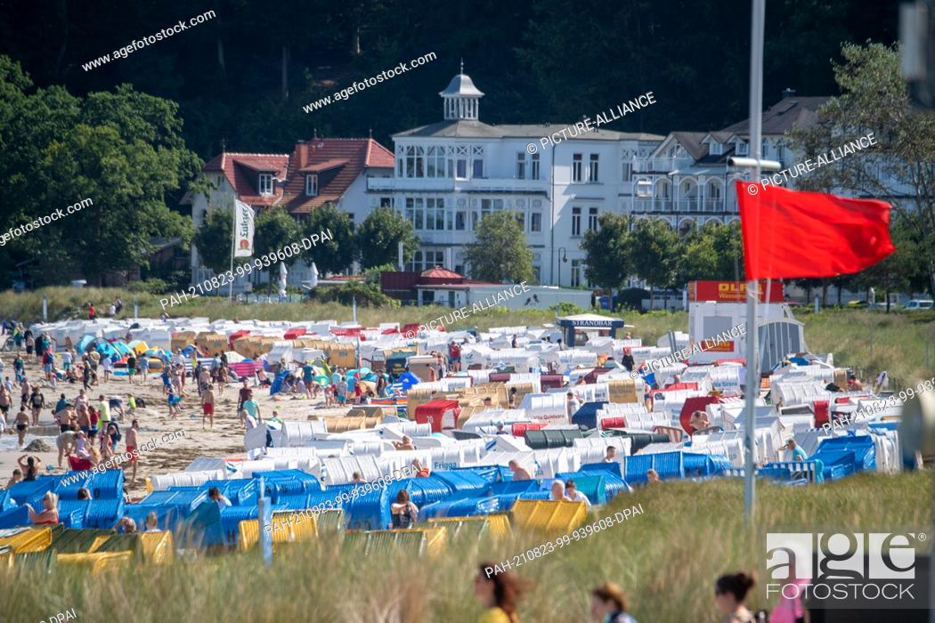 Stock Photo: 23 August 2021, Mecklenburg-Western Pomerania, Binz: On the Baltic Sea beach, a red flag on the DLRG tower signals that ""bathing and swimming are forbidden"".