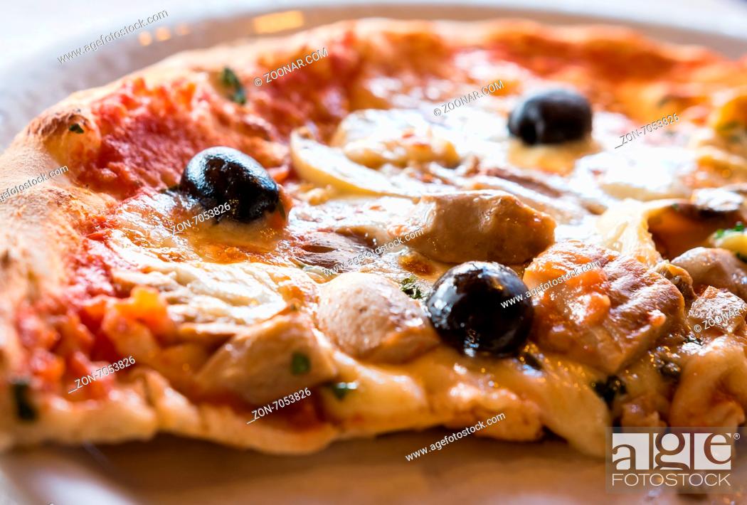 Stock Photo: A close-up image of a slice Italian pizza with olives , mushrooms and herbs .