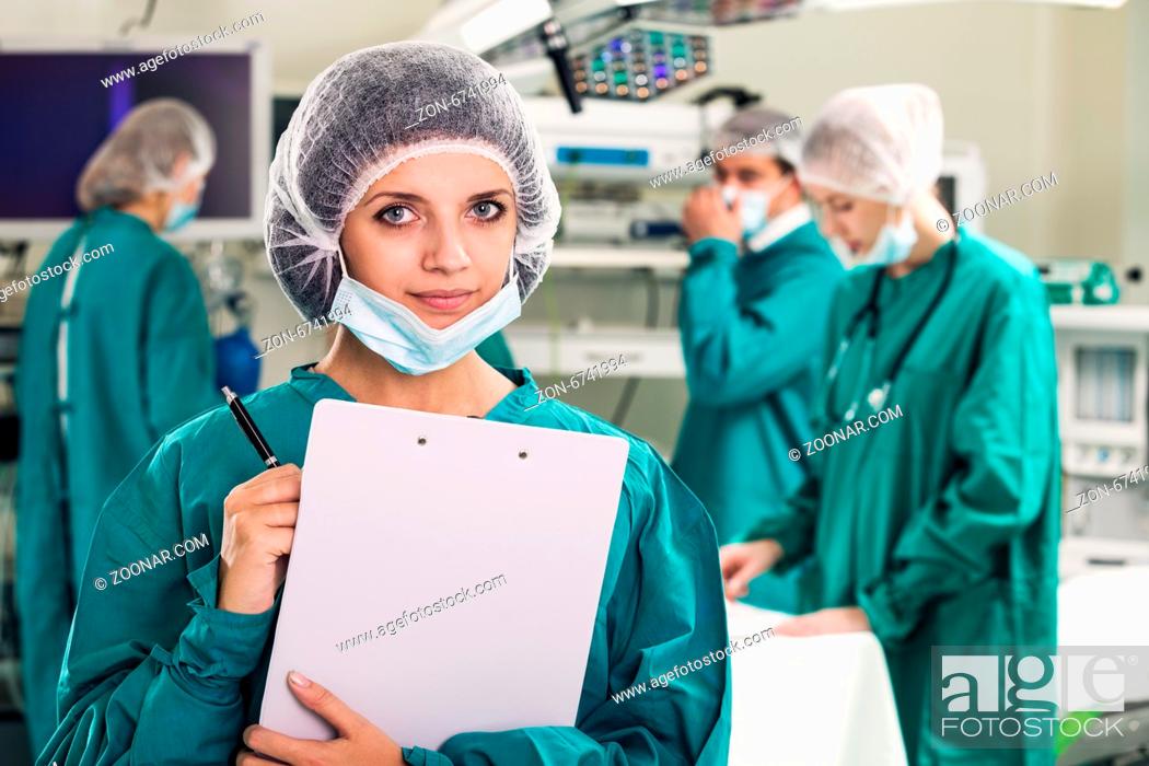 Stock Photo: Portrait of surgeons in surgery with doctors working on background.