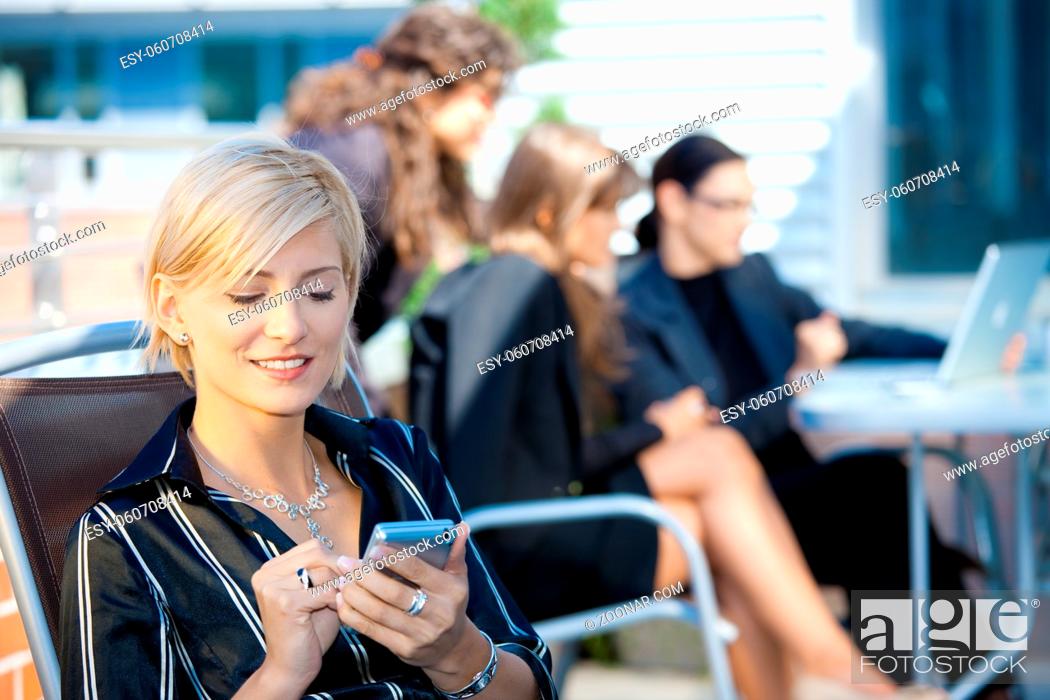 Stock Photo: Young businesswoman using smart mobile phone, outside office building.