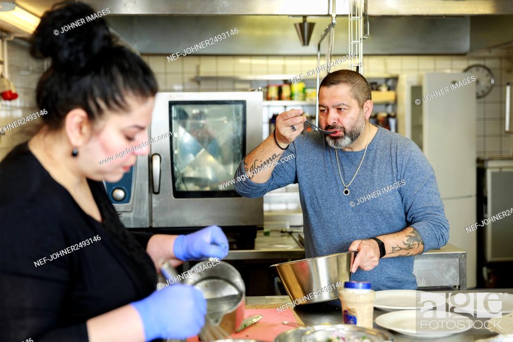 Stock Photo: Man and woman preparing food in restaurant kitchen.
