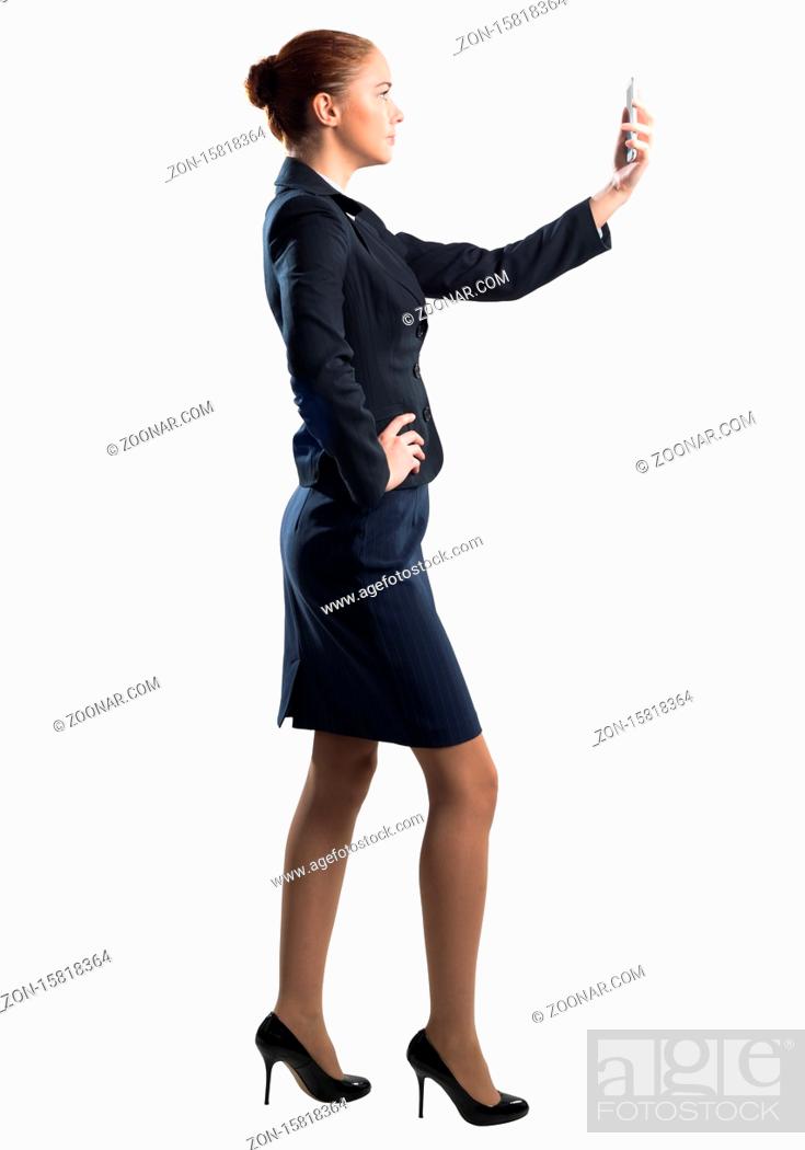 Stock Photo: Young beautiful woman taking selfie photo with smartphone. Confident and stylish businesswoman in dark blue suit. Corporate businessperson isolated on white.